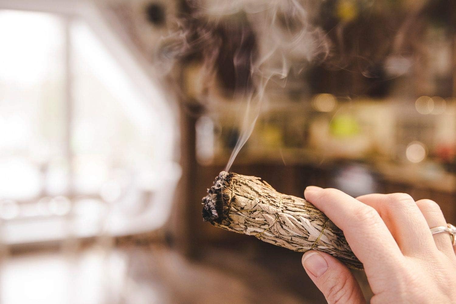 Hand holding a smoking incense stick with a blurred background